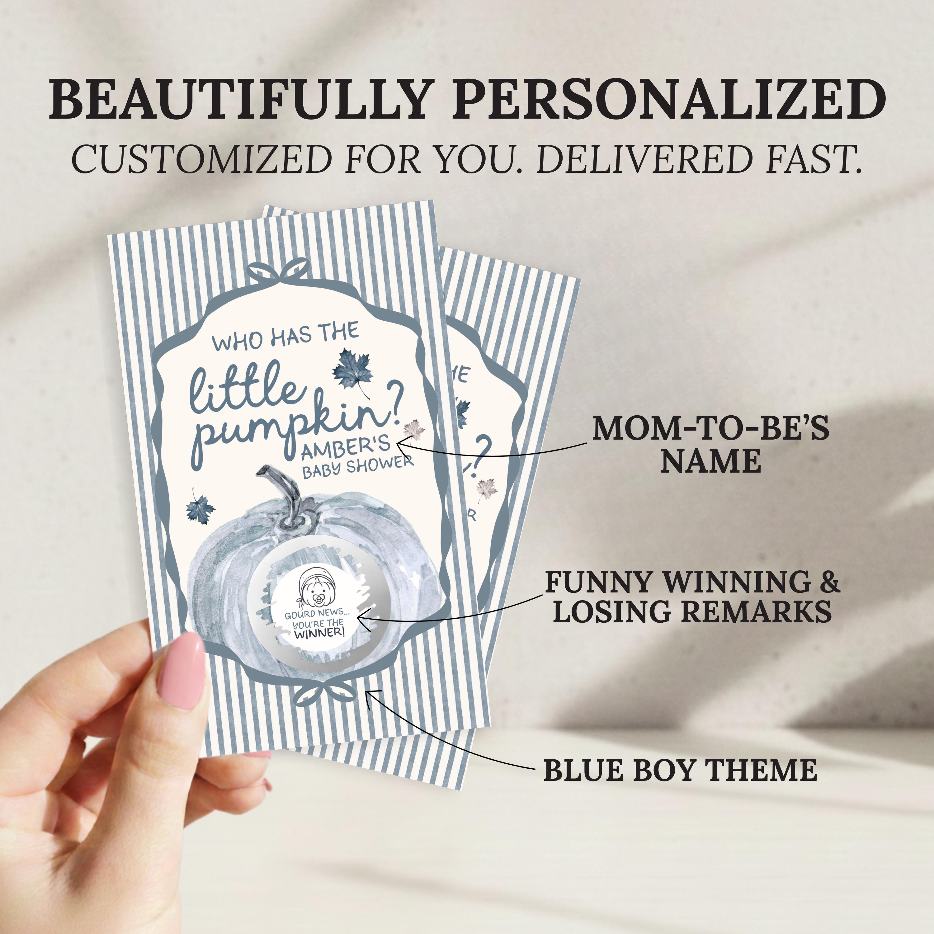 A hand holding a personalized baby shower invitation card with a pumpkin theme.